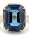 Gold ring with a large blue gemstone on a white background