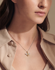 Close-up of a woman wearing a necklace with a bee pendant, set against a neutral background.