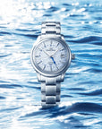 Silver watch with blue dial on a blue water background