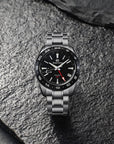 Silver watch with black face on a textured stone surface