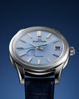 Luxury watch with blue face and dark blue strap on a gradient blue background
