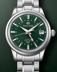 Grand Seiko watch with green dial and silver metal bracelet on a dark green background