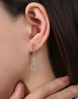 Close-up of an ear wearing a diamond earring with a neutral background