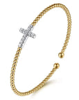 Gold beaded bracelet with a white gold cross charm on a white background