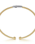 Gold beaded bracelet with a white gold cross on a white background side view