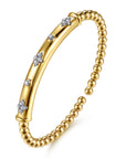A gold cuff bangle bracelet featuring a polished central bar decorated with small star-shaped and round diamond accents, flanked by a beaded chain of gold beads, shown on a white background. angled