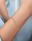 Gold bracelet on a person's wrist against a light blue background