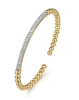 Gold bangle with diamond accents on a white background angled