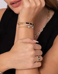 Close-up of a person wearing gold jewelry including a necklace, bracelet, and ring.
