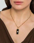 Gold necklace with a black pendant worn by a person
