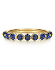 A yellow gold ring featuring nine round-cut blue sapphire gemstones, shown on a clean white background. The brand name 'GABRIEL & CO.