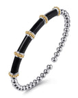 A two-tone stretch bangle bracelet featuring a glossy black central tube section with gold and silver metallic accents, connected to a silver beaded section, shown on a white background. Angled