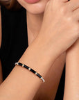 Close-up of a person wearing a black beaded bracelet on a plain background
