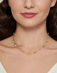 Woman wearing a gold necklace with round beads on a plain background