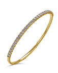A bold 14k yellow gold rigid oval bangle bracelet from the 1.90 carat variant option, showcasing a single row of substantial, large round brilliant diamonds across the top half. angled view