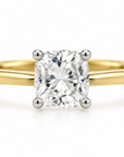 A classic solitaire engagement ring featuring a cushion-cut diamond set in a four-prong white gold or platinum band with a polished yellow gold shank, shown on a clean white background.