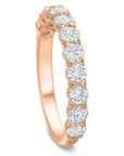 A rose gold ring featuring a row of round brilliant-cut clear gemstones set in a polished band, shown on a clean white background.