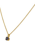 Gold necklace with a blue gemstone pendant on a white background angled side view