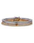 Three diamond-studded bangles in gold, silver, and rose gold on a white background