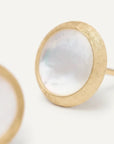 Gold earrings with a white stone on a light background close up