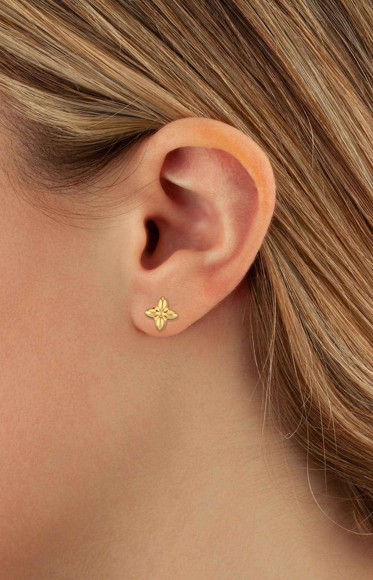 Gold earring worn by a person with blonde hair.