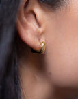close up of a person wearing a gold square hoop earring
