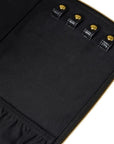 Close-up of a black fabric zippered pouch or organizer with four gold-tone snap buttons and gold zipper trim on a white background.