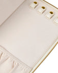 Close-up of a blush fabric zippered pouch or organizer with four gold-tone snap buttons and gold zipper trim on a white background.