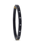 Black bracelet with gold accents and embedded stones on a white background tilted angle