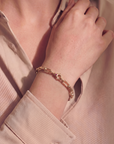 Close-up of a hand wearing a gold bracelet with a pink shirt.