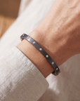 close up of an arm with a black bracelet with embedded diamonds