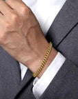 Gold bracelet on a person wearing a gray suit and white shirt