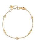 Gold bracelet with flower charm and ruby stone on a white background