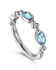 Silver ring with blue gemstones on a white background angled