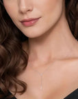 Close-up of a woman wearing a delicate silver necklace with a black background