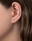 silver hoop earring worn by a person with brown hair.