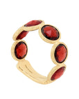 A gold band ring featuring five rose-cut deep red gemstones set in a textured bezel setting, photographed on a clean off-white background.