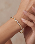 gold bracelet with multi shaped diamonds on a wrist on a neutral background