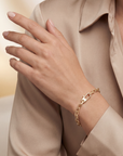 Gold bracelet on a hand with a neutral background