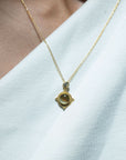 Gold necklace with a diamond and cats eye chrysoberyl pendant on a white background