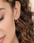 Close-up of a woman wearing a gold hoop earring with a neutral background