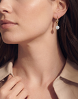 Close-up of a woman wearing gold earrings with a neutral background