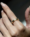 Gold ring with diamonds on a person's finger against a dark background