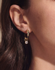 close up of person with brown hair wearing black and gold hoops with a diamond dangle