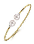 Gold bracelet with two pearls on a white background angled