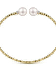 Gold bracelet with two pearls on a white background side view