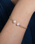 Pearl bracelet on a wrist with a dark blue fabric background