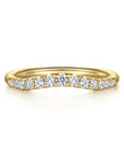 A Gabriel & Co. curved anniversary band, showcasing a contoured line of round brilliant-cut diamonds set in high-polish 14k yellow gold, sculpted to fit flush against an engagement ring.
