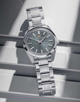 Silver watch with a dark face on a reflective surface