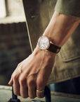 Hand wearing a watch with a blurred background